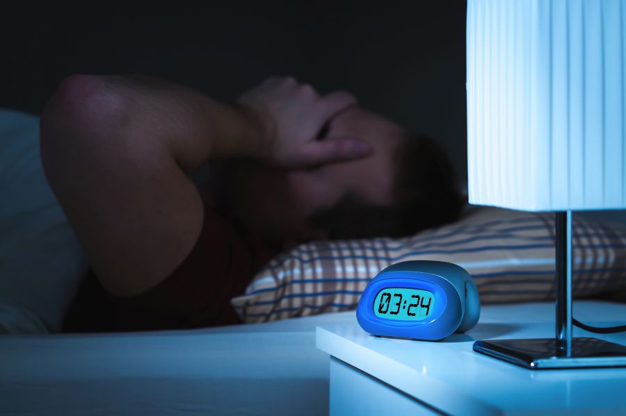 Homme dans son lit souffrant d'insomnie à cause de sa charge de travail