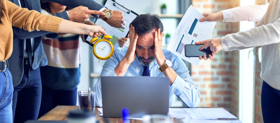 Dirigeant d'entreprise se tenant la tête à deux mains à cause de la surcharge de travail